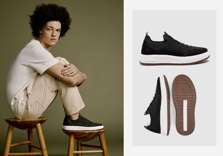 Homem sentado com tênis preto estilo casual.