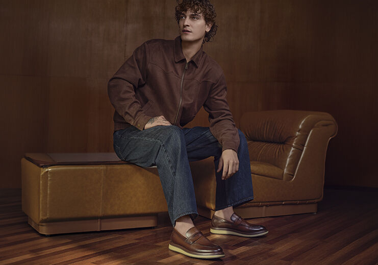 Homem com sapatos sociais sentado em sofá de couro