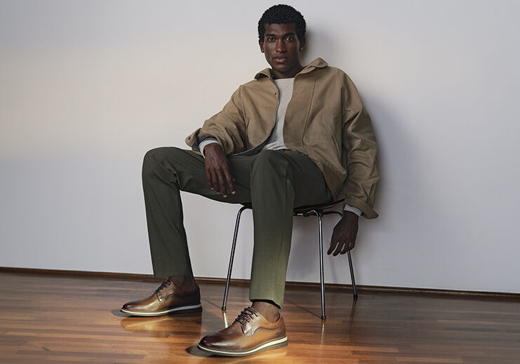 Homem sentado em cadeira com roupas estilosas e sapatos