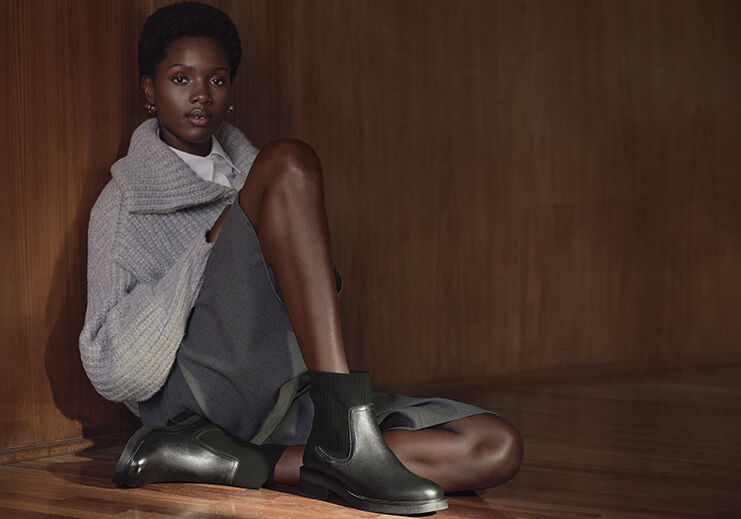 Modelo sentada usando botinas pretas em ambiente elegante