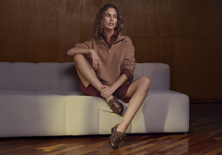 Modelo feminina sentada usando roupas casuais e sapatos