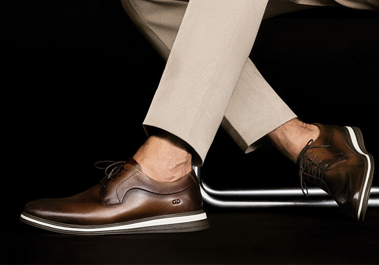 Sapatos sociais masculinos marrons em fundo escuro