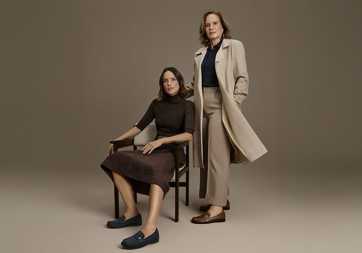 Duas mulheres elegantes em ambiente neutro.