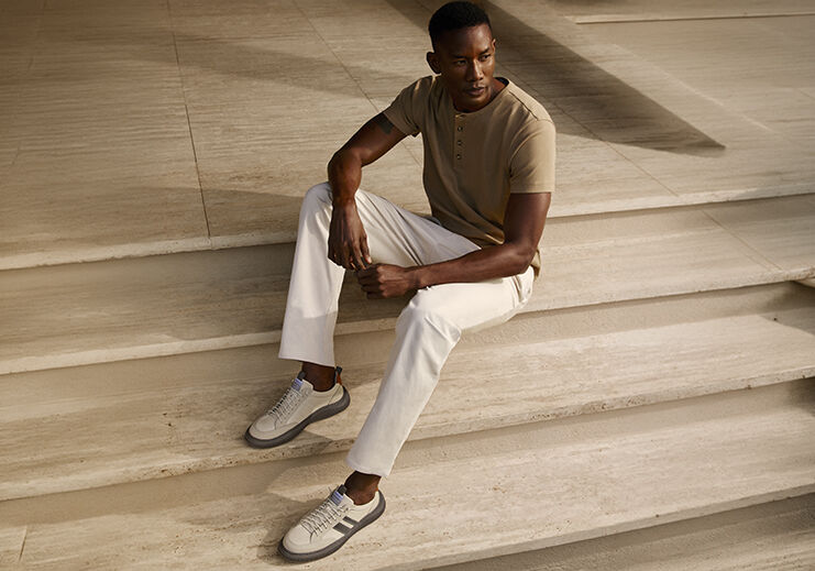 Homem sentado em escadas com roupa casual