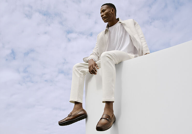 Homem sentado em altura com traje claro e sapatos marrons