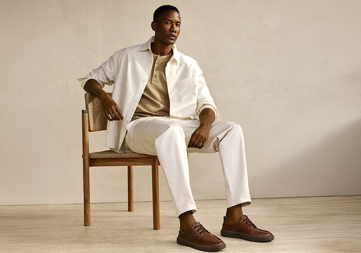 Homem sentado em cadeira usando roupas elegantes.