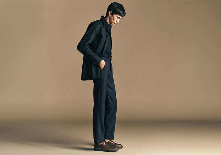Modelo masculino em traje escuro sobre fundo neutro