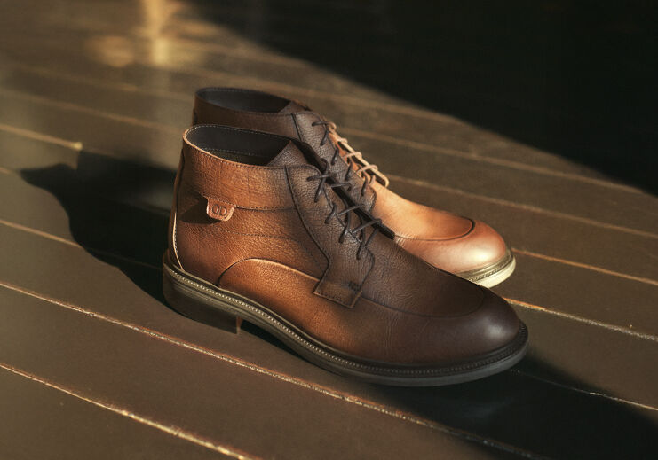 Botas de couro marrom em fundo de madeira