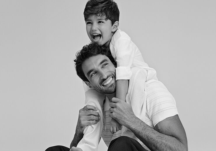 Pai e filho sorrindo em estúdio fotográfico.