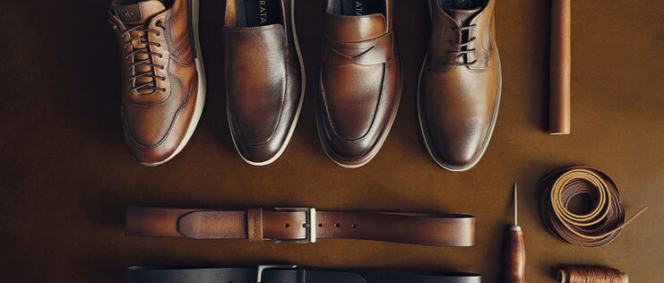 Sapatos e cintos de couro masculino em fundo marrom.